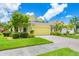Bright yellow home with a lush green lawn, palm trees, and a brick driveway on a sunny day at 2085 Mattamy Ct, Venice, FL 34292