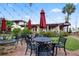 Charming outdoor dining area with black metal tables, umbrellas, firepit, and lush landscaping at the local restaurant at 2085 Mattamy Ct, Venice, FL 34292