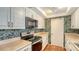 Compact kitchen showcasing stainless steel appliances, white cabinetry, and tiled floors at 222 Beach Rd # 7, Sarasota, FL 34242