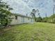 A spacious backyard showing the home's exterior and ample green space at 2403 Trianna St, North Port, FL 34291