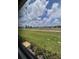 Expansive, lush green backyard view framed by a serene, cloudy sky at 24827 Buckingham Way, Port Charlotte, FL 33980