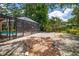 A backyard view featuring a screened-in pool, stone landscaping, and lush tropical plants and trees at 2515 Huntington Ave, Sarasota, FL 34232