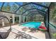 Sparkling blue pool in a screened enclosure, complemented by a cozy seating area and lush greenery at 2515 Huntington Ave, Sarasota, FL 34232