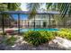 A screened-in pool surrounded by lush greenery, offering a private retreat with tropical plants and sunshine at 2515 Huntington Ave, Sarasota, FL 34232