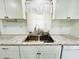 Close-up of kitchen sink featuring white cabinets and granite countertop at 3222 Sycamore Ter, Sarasota, FL 34237