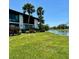 Picturesque backyard view with lush green lawn, a tranquil lake, and mature palm trees under a blue sky at 3500 El Conquistador Pkwy # 347, Bradenton, FL 34210