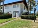 Inviting two-story condo with white exterior, brown trim, lush landscaping, and an iron gate entry at 3500 El Conquistador Pkwy # 347, Bradenton, FL 34210