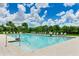 Sparkling community pool with lounge chairs, lush landscaping, and sunny blue skies with picturesque clouds at 3504 Big Sky Way, Bradenton, FL 34211