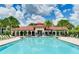 A sparkling community pool with nearby clubhouse, lounge chairs, tables, umbrellas and palm trees at 3504 Big Sky Way, Bradenton, FL 34211