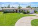 Well-kept single-story home featuring a lush green lawn and a circular driveway at 3621 S Lockwood Ridge Rd, Sarasota, FL 34239