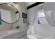 Well-lit bathroom featuring white vanity with granite countertop, round mirror, and a tub with shower and white tiles at 4120 51St W Dr, Bradenton, FL 34210