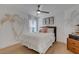 Bright bedroom with hardwood floors, large window, palm tree wall art, and a ceiling fan at 4120 51St W Dr, Bradenton, FL 34210