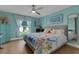 Light-filled bedroom with hardwood floors, ceiling fan, coastal decor, and large windows overlooking the front yard at 4120 51St W Dr, Bradenton, FL 34210