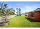 Spacious backyard featuring lush green lawn, a white fence, and a charming garden area alongside the orange home at 4194 Banbury Cir, Parrish, FL 34219