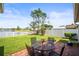 Enjoy a peaceful backyard with brick patio, outdoor seating, and serene views of the lake beyond a white picket fence at 4194 Banbury Cir, Parrish, FL 34219