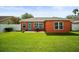Spacious backyard with lush lawn, brick patio, outdoor seating, and a vibrant orange home exterior with a blue door at 4194 Banbury Cir, Parrish, FL 34219