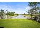 Expansive backyard with lush green lawn, a charming white fence bordering a serene lake, and picturesque landscaping at 4194 Banbury Cir, Parrish, FL 34219