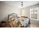 Cozy bedroom featuring a metal-framed bed with a colorful quilt, a side table with lamp, and plantation shutters at 4194 Banbury Cir, Parrish, FL 34219