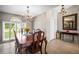 Elegant dining room with arched window, chandelier, wooden table and chairs, and tile flooring at 4194 Banbury Cir, Parrish, FL 34219
