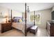 Comfortable bedroom with a four-poster bed, side table, and a window bringing in natural light at 4194 Banbury Cir, Parrish, FL 34219