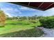 Outdoor landscape view from a patio, showcasing a serene pond surrounded by lush greenery and a blue sky at 4227 Placid Dr, Sarasota, FL 34243