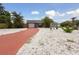 Charming single-story home with a red driveway, white rock landscaping, and vibrant tropical foliage at 4303 83Rd W St, Bradenton, FL 34209