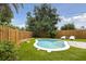 Private backyard oasis featuring a kidney-shaped pool surrounded by green grass, lounge chairs, and a wood fence at 4303 83Rd W St, Bradenton, FL 34209