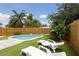 Backyard with a kidney-shaped pool, wooden fence, tropical foliage, lounge chairs and small table at 4303 83Rd W St, Bradenton, FL 34209