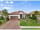 Beautiful single-story home with a red tile roof, brick driveway, lush landscaping, and a two-car garage at 4720 Arpino Ct, Bradenton, FL 34211