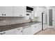 Well-lit kitchen features white cabinetry, marble backsplash, stainless steel appliances, and wood flooring at 4720 Arpino Ct, Bradenton, FL 34211