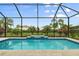 Beautiful pool with integrated tile waterfall feature amidst lush landscaping within screened enclosure at 4720 Arpino Ct, Bradenton, FL 34211