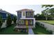 Modern two-story home features a minimalist design, yellow door, and welcoming front porch with seating at 4759 11Th S Ave, St Petersburg, FL 33711