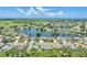 Aerial view showcasing a neighborhood with homes bordering a tranquil lake, reflecting the clear blue sky and surrounding landscape at 5142 51St W Ln, Bradenton, FL 34210