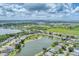 Aerial view of a community of homes, situated next to a tranquil lake, with lush green surroundings at 5142 51St W Ln, Bradenton, FL 34210