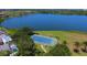 Scenic aerial view of a tennis court by a lake, surrounded by trees, and a glimpse of nearby houses at 5142 51St W Ln, Bradenton, FL 34210