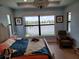 Bedroom with large windows offering serene water views, complemented by tray ceiling with elegant light fixture at 5219 Barnett Cir, Bradenton, FL 34211