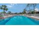 Large, inviting outdoor pool with lounge chairs, tables, and umbrellas under a partly cloudy sky at 5255 Lake Village Dr # 40, Sarasota, FL 34235