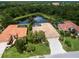 Stunning aerial view of a well-maintained home with a tile roof, lush landscaping, and a serene water view at 6811 Honeysuckle Trl, Lakewood Ranch, FL 34202