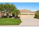 Charming home featuring a tile roof, a well-manicured lawn, palm trees, and a three-car garage at 6811 Honeysuckle Trl, Lakewood Ranch, FL 34202
