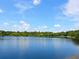 Picturesque lake view with a vibrant blue surface and lush greenery along the shoreline under a clear sky at 6811 Honeysuckle Trl, Lakewood Ranch, FL 34202
