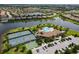 Aerial view of community with club house, pool, pickleball courts, parking, and lake at 7140 Marsh View Ter, Bradenton, FL 34212