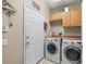 Laundry room with washer, dryer, cabinets, and a white entry door at 743 Stonecrest Dr, Sarasota, FL 34232