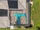 Top-down aerial view of a pool with umbrellas and an attached hot tub inside a screened enclosure and solar panels at 7513 Coventry Ct, Lakewood Ranch, FL 34202