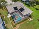 Aerial view of a house with solar panels and a screened-in pool area, backing up to lush green landscaping at 7513 Coventry Ct, Lakewood Ranch, FL 34202