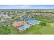 Aerial view showcases a clubhouse with a pool, tennis courts, and a parking lot at 8382 Creekview Ln, Englewood, FL 34224