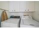 Practical laundry room equipped with a washer, dryer, overhead cabinets, and ironing board for efficient household tasks at 8382 Creekview Ln, Englewood, FL 34224
