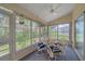 The bright sunroom offers a tranquil retreat with comfortable seating, a ceiling fan, and panoramic views at 8382 Creekview Ln, Englewood, FL 34224