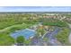 Overhead shot displays the community's tennis courts, a pool, parking, and lush landscaping at 8382 Creekview Ln, Englewood, FL 34224