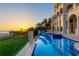 Stunning view of an infinity pool at sunset, with a large home and beach in the background at 845 Longboat Club Rd, Longboat Key, FL 34228