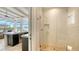 Modern bathroom with a glass shower and an opening displaying the outdoor kitchen and backyard beyond at 8537 Pavia Way, Bradenton, FL 34202
